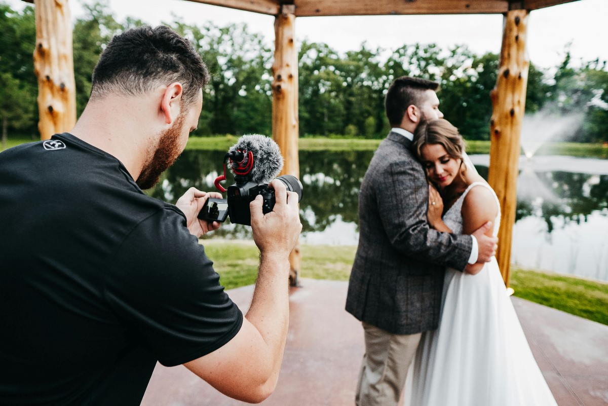 Photographer taking a picture of the bride and groom outdoors